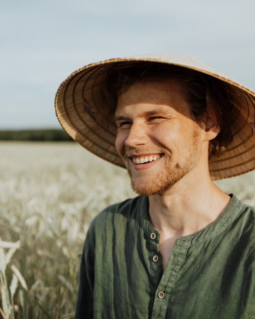 A man wearing a hat standing in the middle of a field.