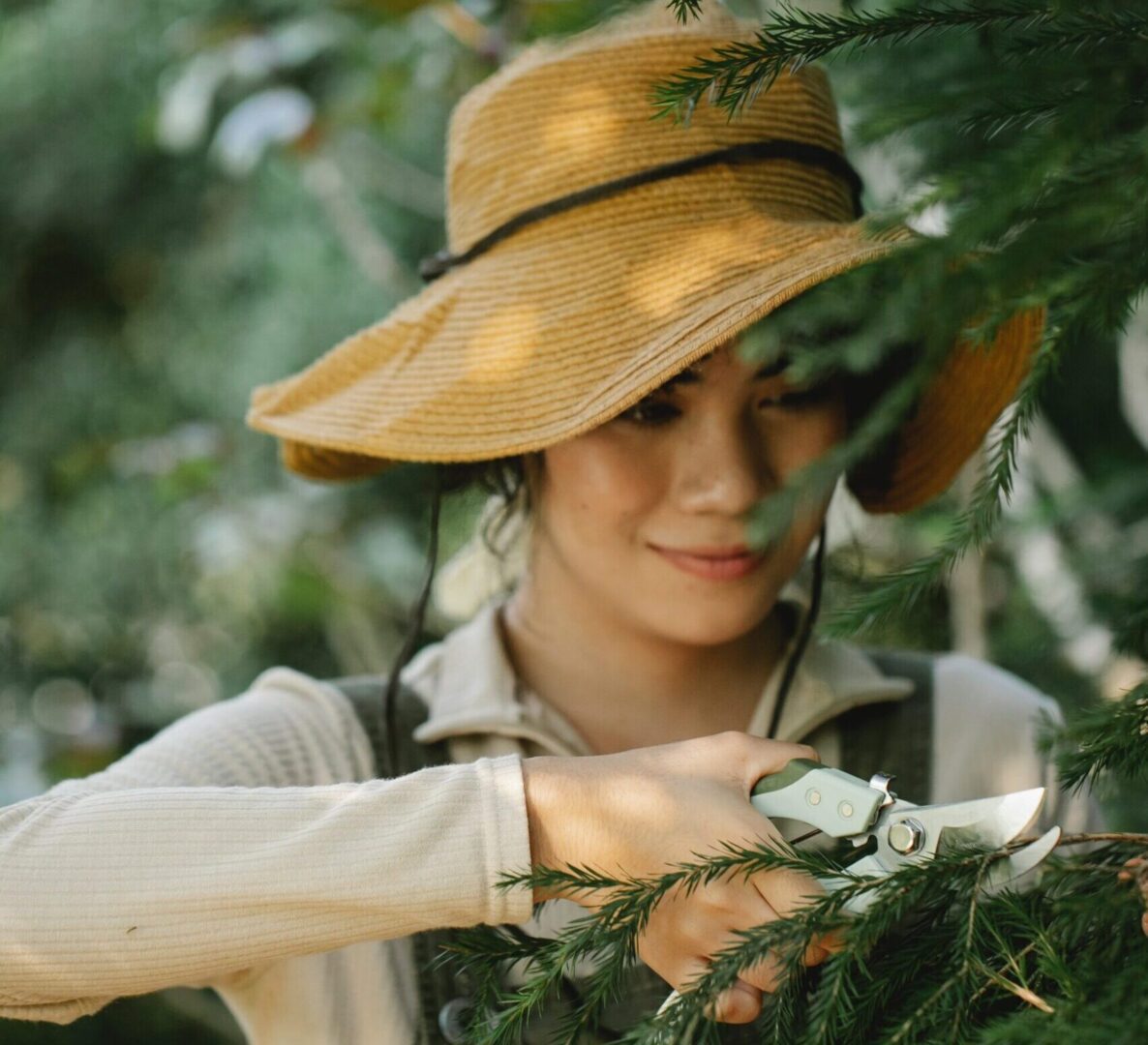 A woman in a hat and glasses is looking at the camera.